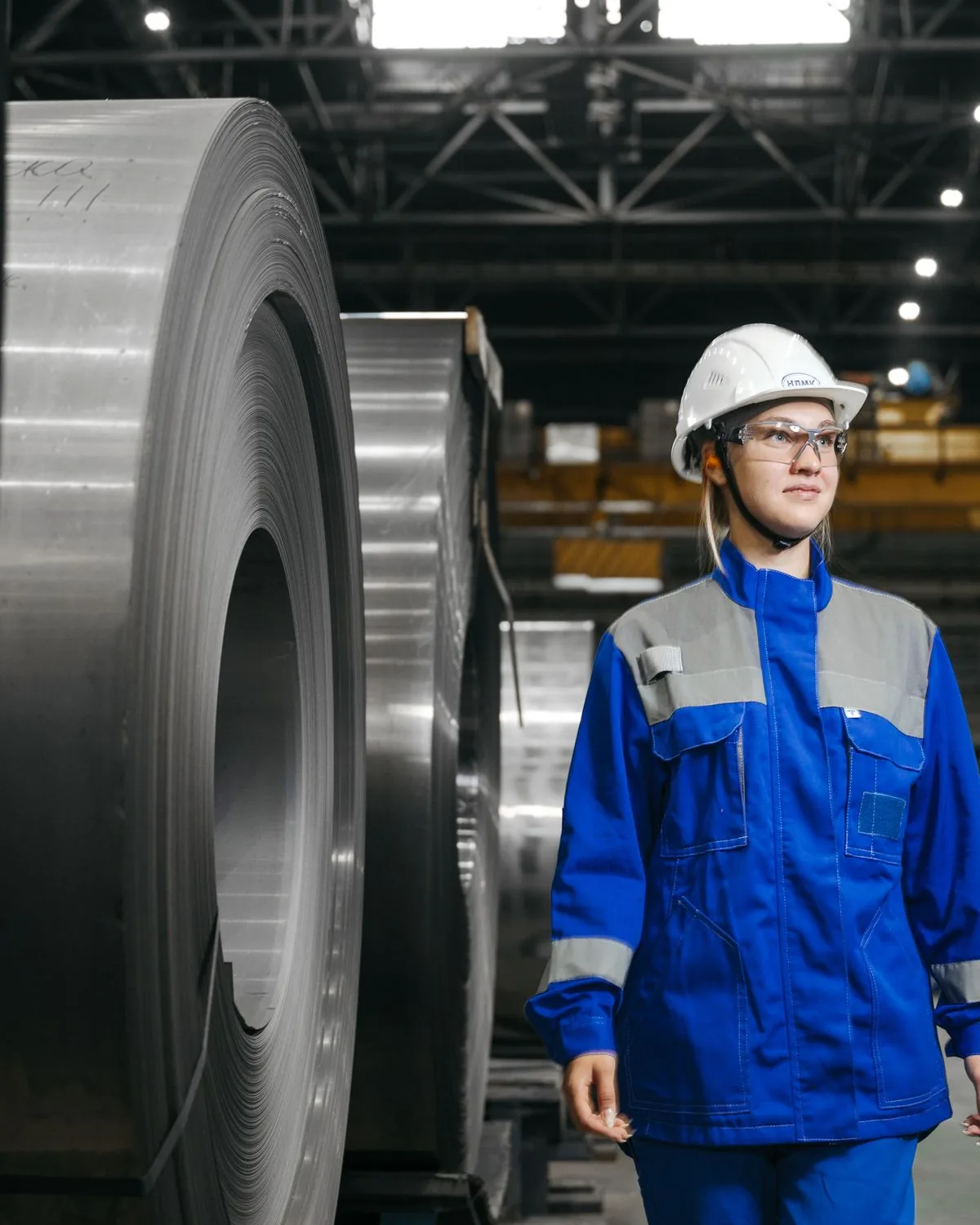 Trabajadora con casco y ambo en una planta industrial